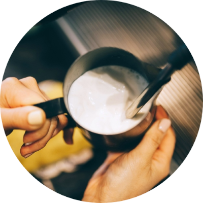 Barista steaming milk in jug